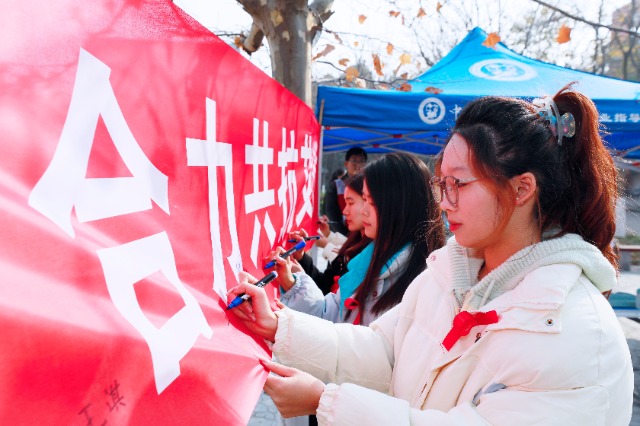 20231127中國(guó)石油大學(xué)（華東）青年學(xué)子在合力共抗艾滋的條幅上簽字，表達(dá)抗擊艾滋病的決心和信心  .jpg