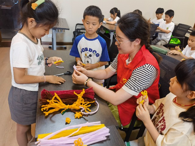 7月12日，在泰州市海陵區(qū)城東街道林湖社區(qū)，泰州市大浦小學(xué)“綠葉”暑期公益班的老師正在教孩子們一起做手工2（拍攝者：泰州市大浦中心小學(xué)  陳惠婷）.jpg